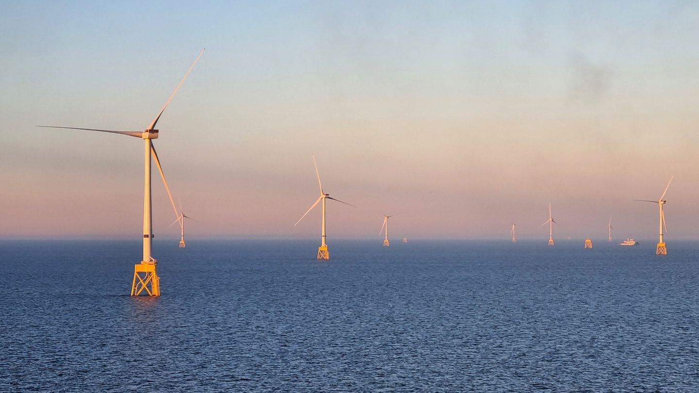 The picture shows several windmills standing in the ocean.