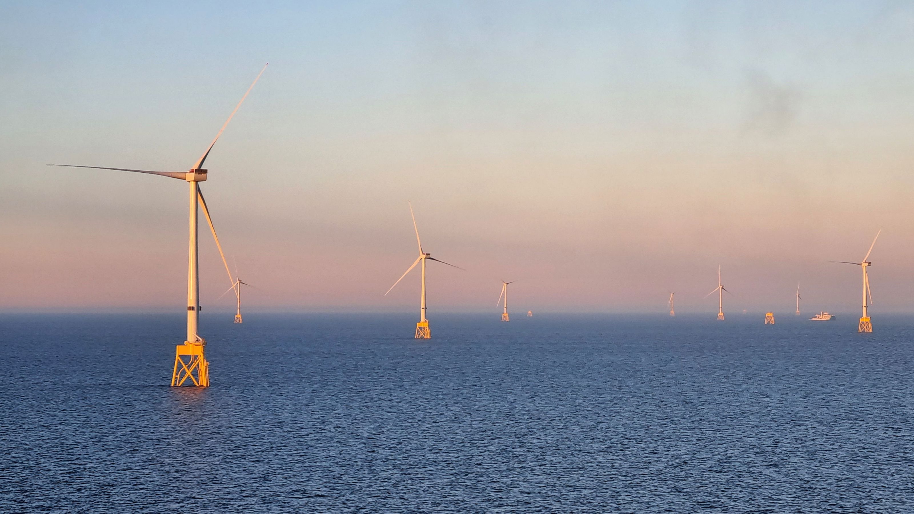 The picture shows several windmills standing in the ocean.